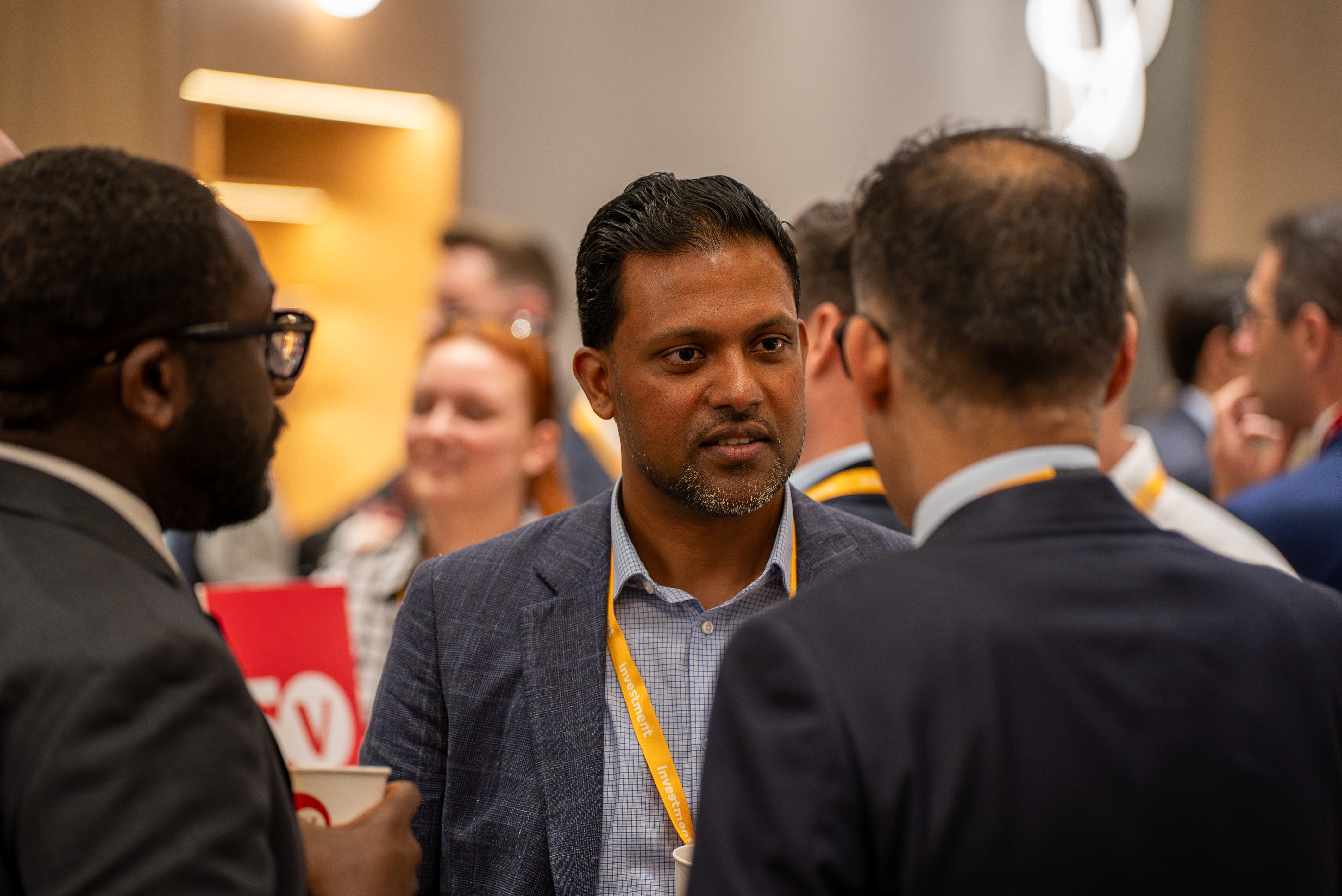 Three conference attendees from the investment stream talking during a break
